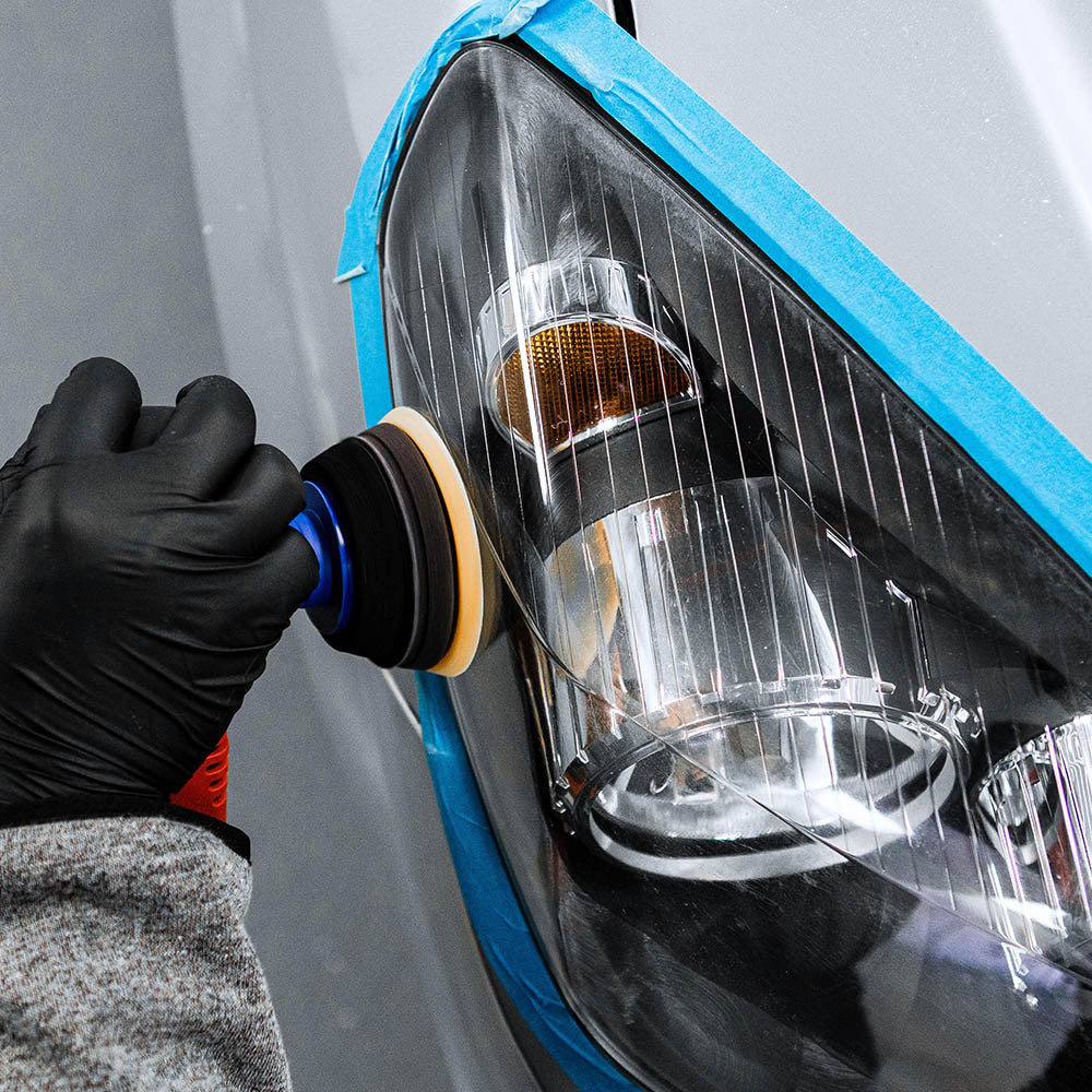 A taped off headlight being machine polished using Koch Chemie Headlight Polish 2 | High-Gloss Headlight Polish with Sealant