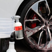 Koch Chemie Magic Wheel Cleaner | Acid Free Rim Cleaner 500ml resting on a car wash bucket with the product sprayed on a wheel in the background